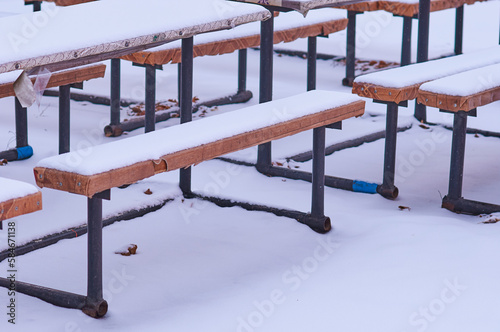 Tables and benches in a street cafe are covered with snow in winter. No people. Harsh continental climate. Tourism business seasonality concept.