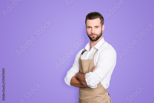 Portrait with copyspace, empty place for advertisement of half turned, concentrated attractive barber in shirt having his arms crossed, looking at camera, isolated on grey background © deagreez