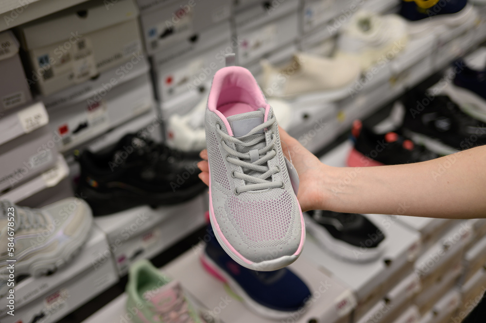 A woman chooses shoes in a shopping center in the sporting goods department, close-up. The concept of female shopping. A woman chooses shoes in a shopping center in the sporting goods department, close-up. The concept of female shopping.