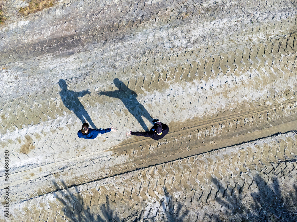 Aerial view landscape. Two figures and their shadows. A couple trying to grasp each other's hands.