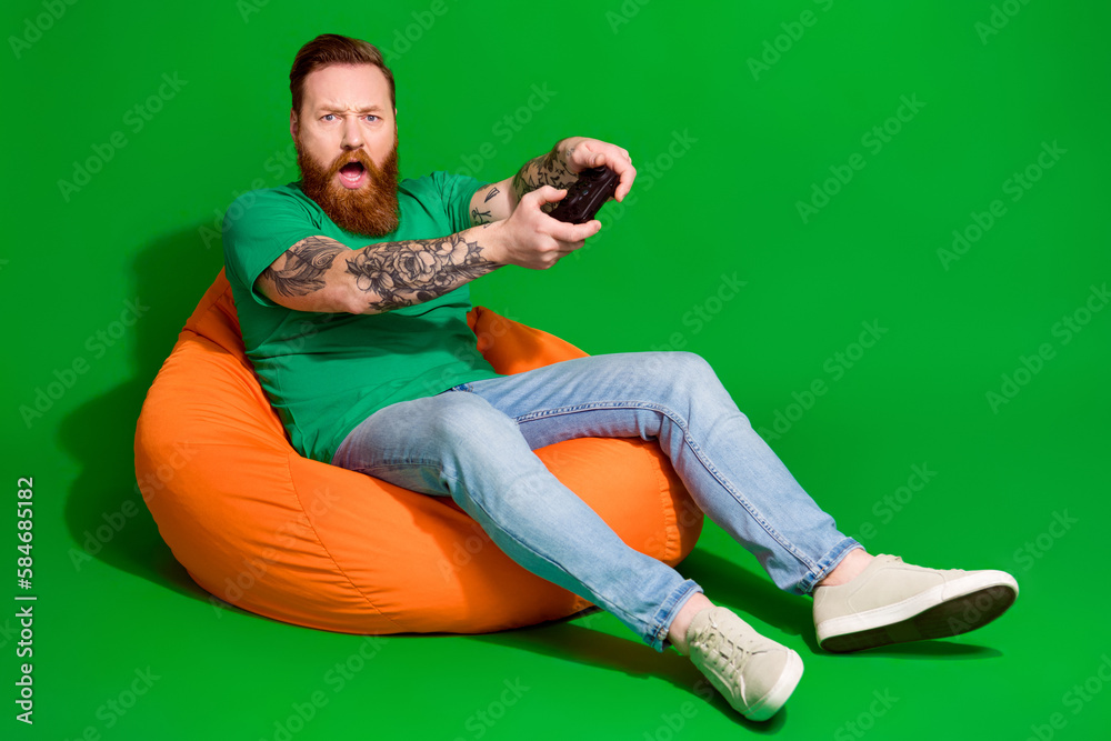 Full length photo of impressed funky guy dressed t-shirt enjoying playstation emtpy space isolated green color background - obrazy, fototapety, plakaty 