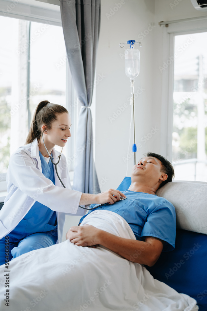  Doctor in white suit take notes while discussing and Asian elderly, man patient who lying on bed with receiving saline solution in hospital or clinic..