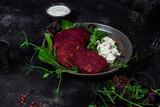 Beetroot pancakes with feta and herbs on a dark plate