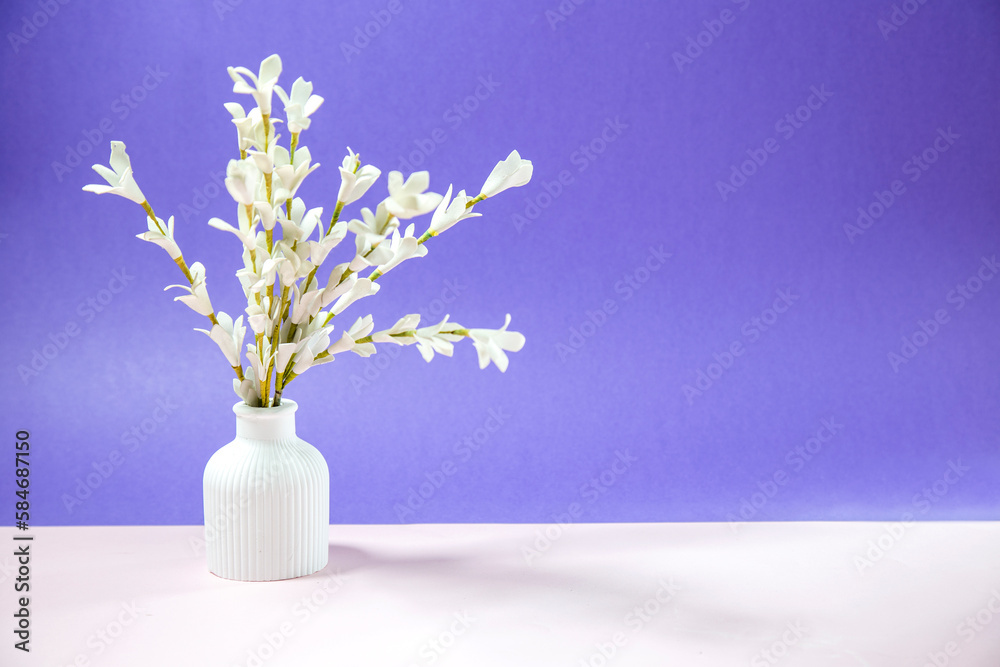 white flowers in vase on white table against purple background white flowers in vase on white table against purple background