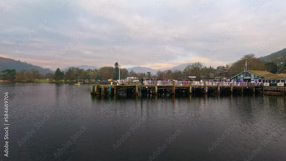 View of the Cumbrian village of Ambleside shot from Lake Windermere. Showing the pier and waiting passengers for the lake cruise. View of the Cumbrian village of Ambleside shot from Lake Windermere. Showing the pier and waiting passengers for the lake cruise.