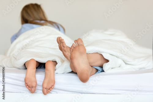 Close-up shot of a couple's legs entangled in bed, capturing the intimacy of their moment together