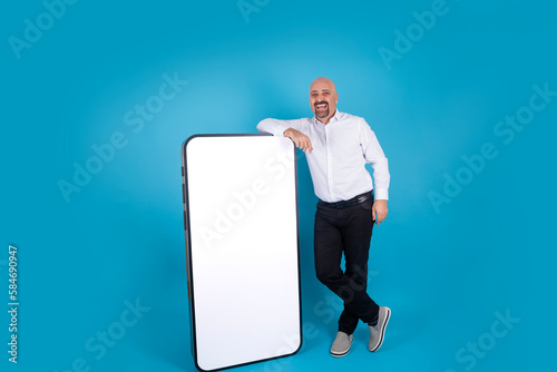 Big cell phone mock up, cheerful middle aged man leaning big cell phone mock up. Empty white screen smartphone for product placement. Application, web site advertising concept idea, copy space. photo