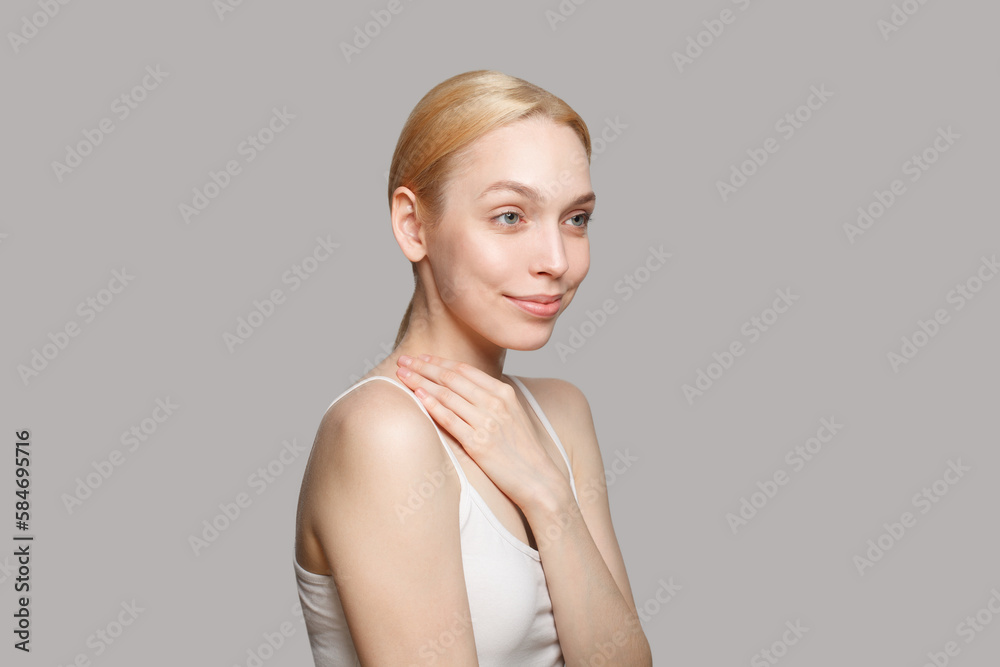 Woman with blonde ponytail standing sideways isolated on grey background. Beauty, cosmetics, skincare, glamour. Woman with blonde ponytail standing sideways isolated on grey background. Beauty, cosmetics, skincare, glamour.