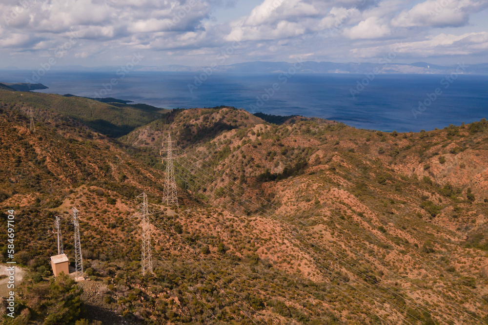 Fototapeta premium Aerial shot of electricity pylons with connected cables on mountains