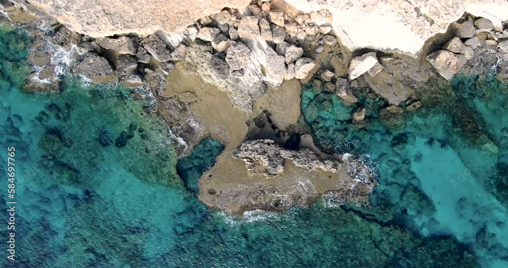 Top view of rocky shore of which is broken by light waves