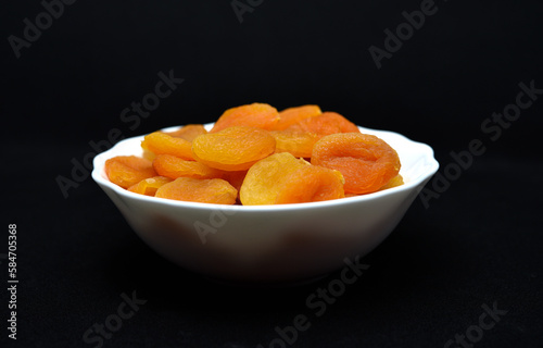 Juicy dried apricots in a white ceramic bowl. Dried apricot fruit halves without a stone.