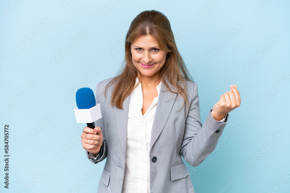 Middle-aged TV presenter woman over isolated blue background making money gesture Middle-aged TV presenter woman over isolated blue background making money gesture