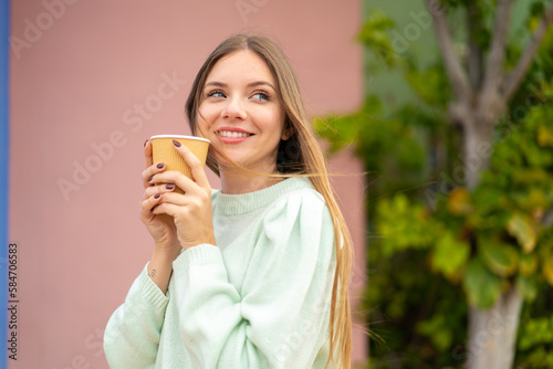 Young pretty blonde woman holding a take away coffee and having doubts