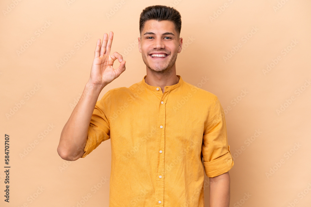 Young caucasian man isolated on beige background showing ok sign with fingers Young caucasian man isolated on beige background showing ok sign with fingers