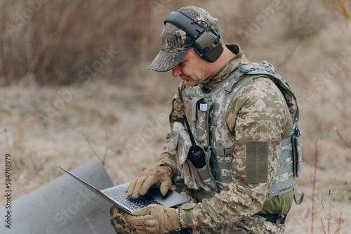 A soldier works on his laptop. A military scout in the field works by coordinates
