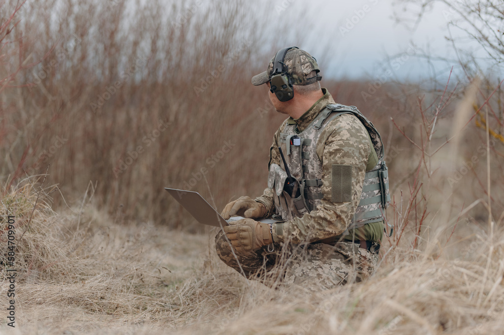 military man stands in camouflage and works with a laptop. military intelligence military man stands in camouflage and works with a laptop. military intelligence