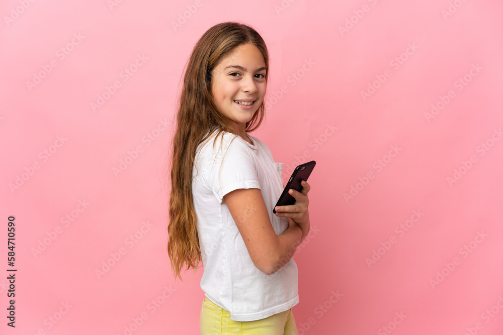 Child over isolated pink background holding a mobile phone and with arms crossed Child over isolated pink background holding a mobile phone and with arms crossed