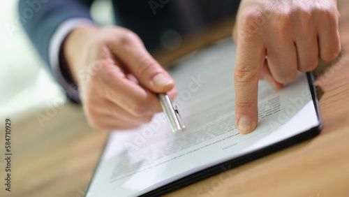 Manager showing client place to sign in document and holding out pen closeup