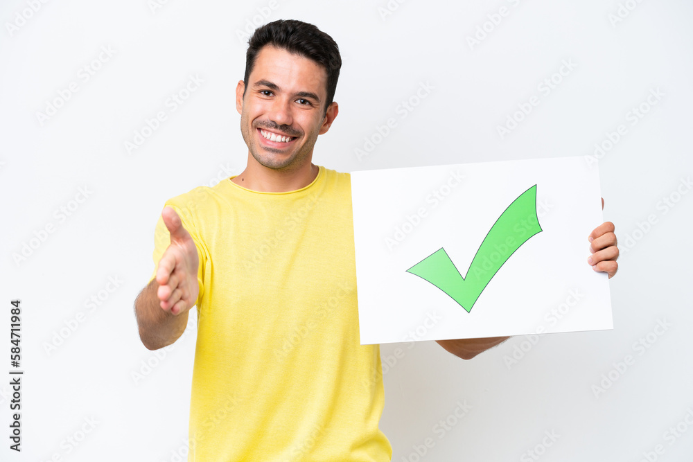 Young handsome man over isolated white background holding a placard with text Green check mark icon making a deal Young handsome man over isolated white background holding a placard with text Green check mark icon making a deal