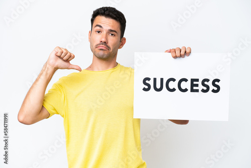 Young handsome man over isolated white background holding a placard with text SUCCESS with proud gesture © luismolinero