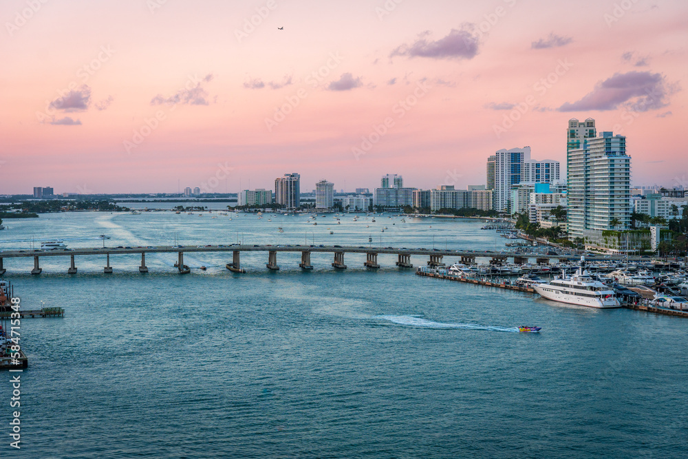 Bridge going across the waterway in Miami with the sunset in the background and the Miami skyline