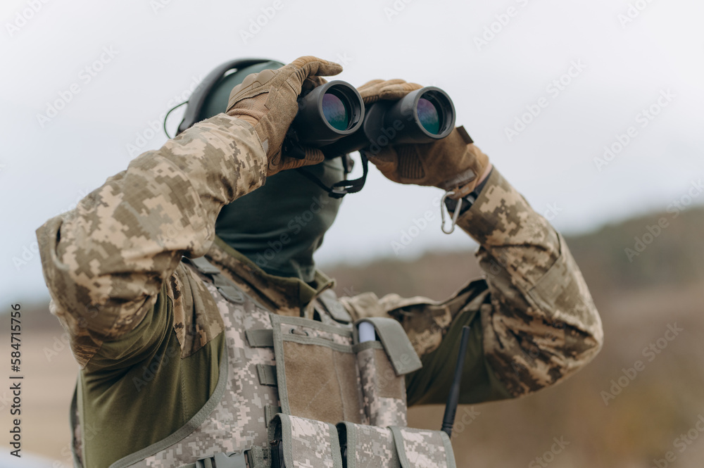 Fototapeta premium war, army, hunting. young soldier, ranger or hunter with binoculars watching the forest