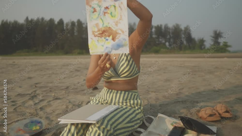 A cheerful artist, inspired by the sunny beach, shows an art of art after it is painted and conceived.