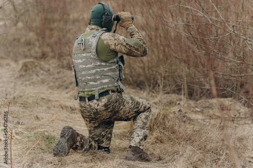 Obraz na plátně a soldier in camouflage holds binoculars
