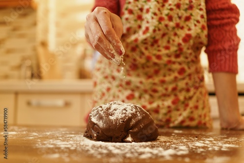 Image of hand sprinkling flour on dough. Close-up of woman sprinkling flour on the dough she kneaded in the kitchen.