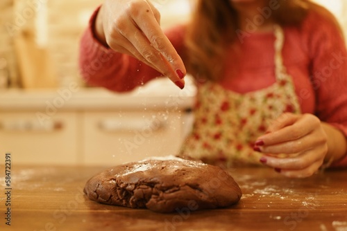 Image of hand sprinkling flour on dough. Close-up of woman sprinkling flour on the dough she kneaded in the kitchen.