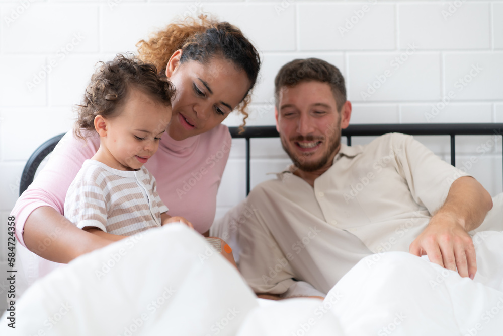 Fototapeta premium Little girl's father read stories to children before going to bed to unwind and sleep soundly until the morning.