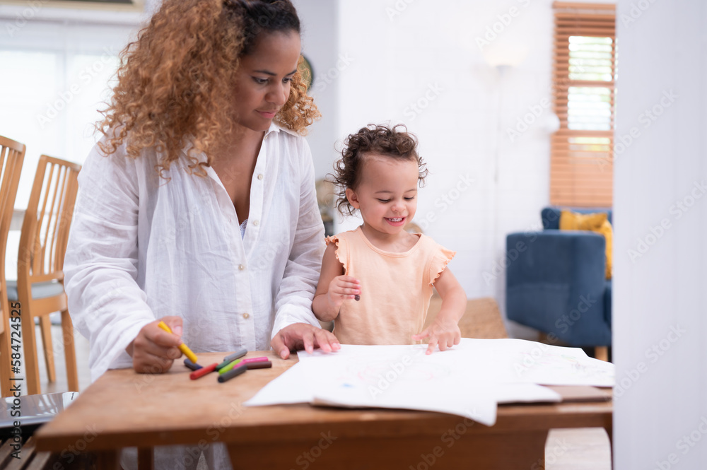 A little child's imagination is represented through colored pencil drawings, with the mother attentively supervising in the living room of the house. A little child's imagination is represented through colored pencil drawings, with the mother attentively supervising in the living room of the house.