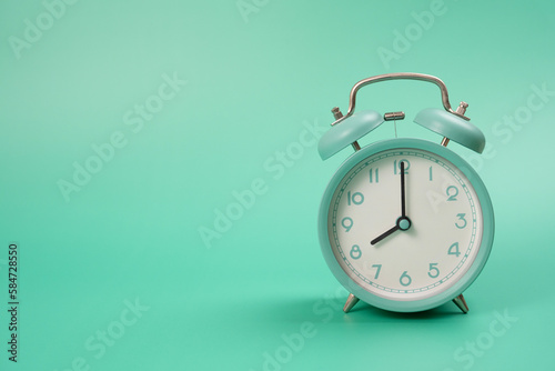 Retro alarm clock on green table background, vintage style, flat lay