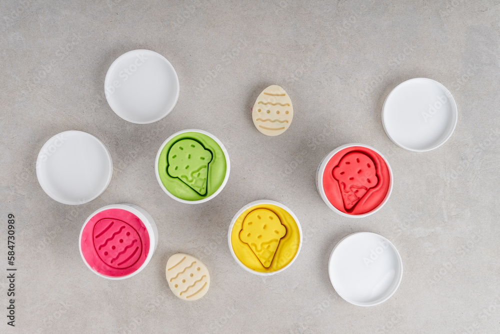 Colorful dough in white jars on gray background. Flat lay