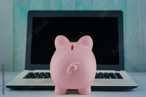 Piggy bank and laptop on table. Concept business finance technology, savings, e-commerce, e-business, deposit or shopping online, wealth from investment, rich profit income, earning, online banking.