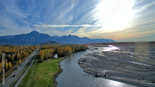 Aerial view of the Matanuska River surrounded by autumn trees against mountains in Palmer, Alaska photo
