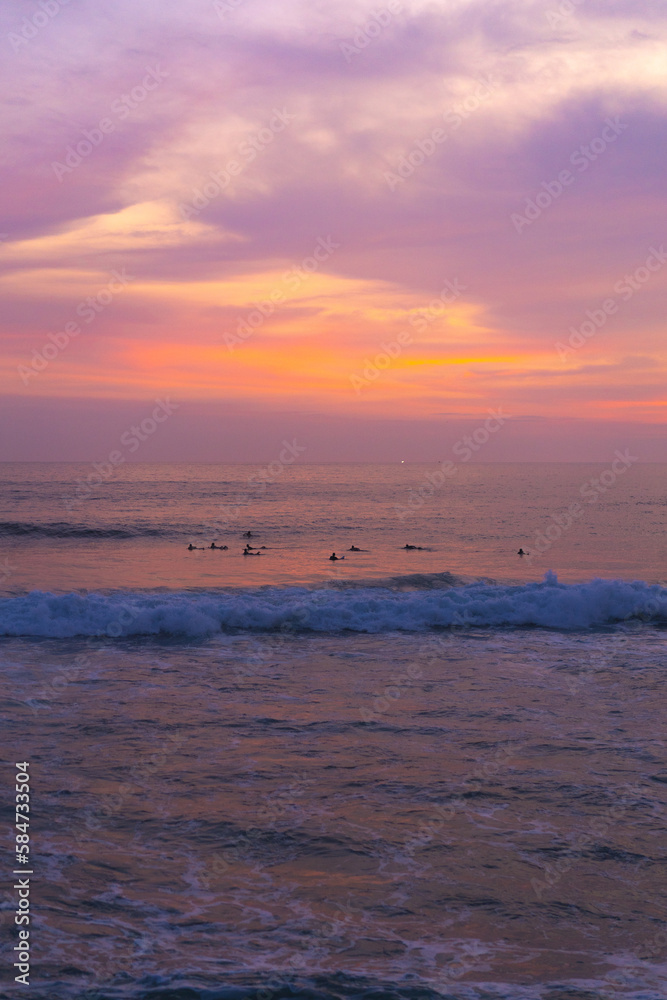 Obraz premium Surfers catch waves, surfing at sunset. Bali.