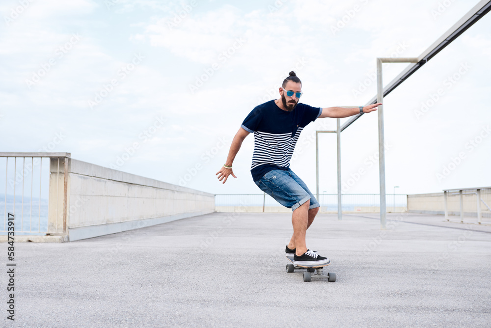 Stylish man in sunglasses skating perfectly on longboard.