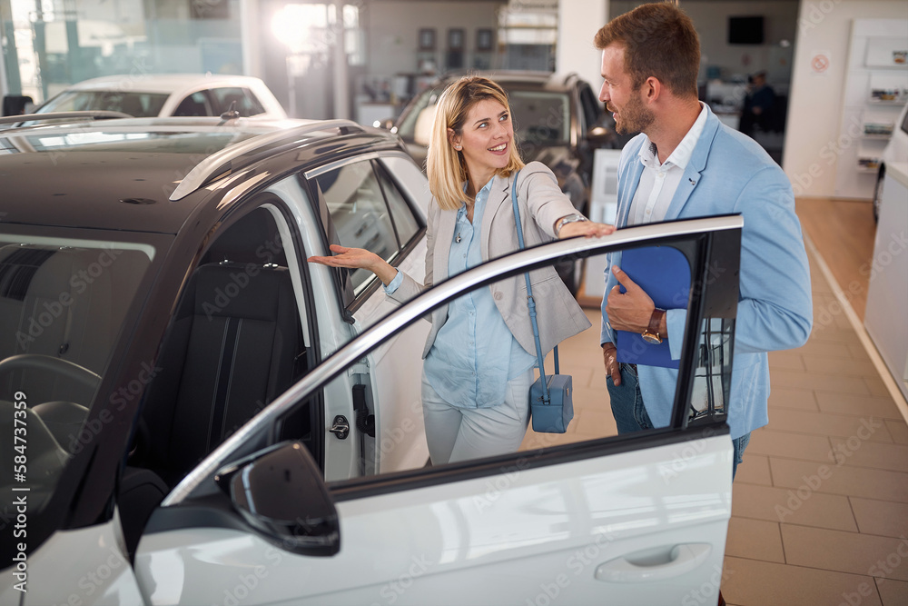 Woman in car showroom with car seller buying  car