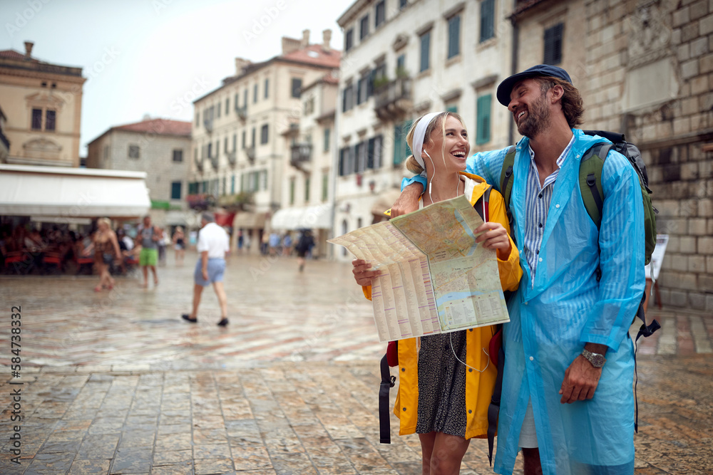 A young couple is using a map while walking the old city during a holiday on the seaside. Vacation, tourists, relationship, seaside
