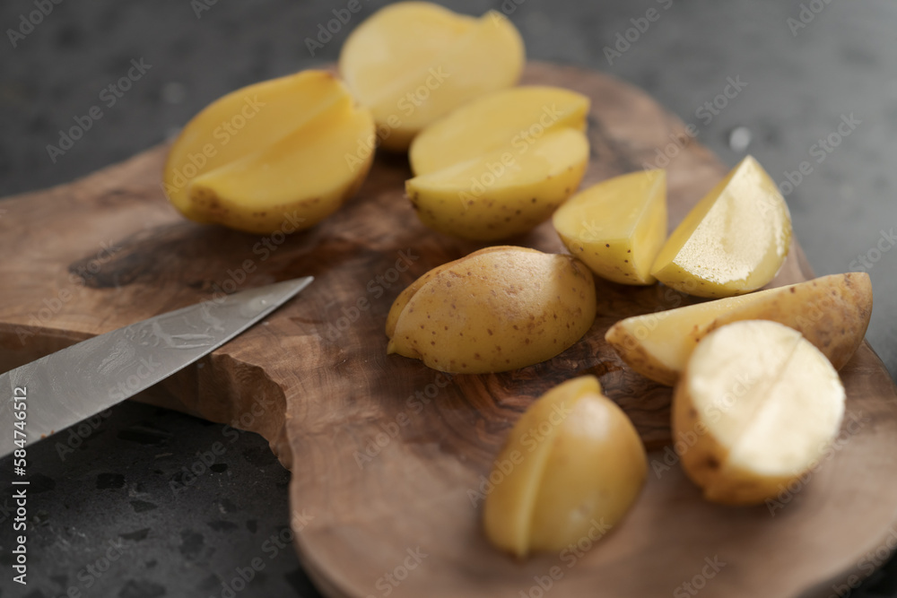 Raw washed and chopped baby potatoes ready to cook on olive wood board Raw washed and chopped baby potatoes ready to cook on olive wood board