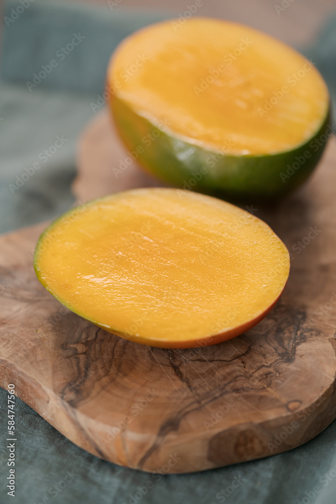 Sliced ripe red mango on olive wood board
