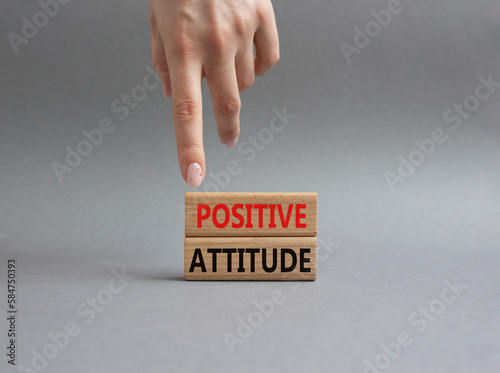 Positive attitude symbol. Concept words Positive attitude on wooden blocks. Beautiful grey background. Businessman hand. Business and Positive attitude concept. Copy space.