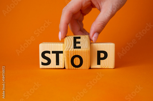Step vs Stop symbol. Businessman hand turns wooden cubes and changes the word Stop to Step. Beautiful orange background. Step vs Stop and business concept. Copy space