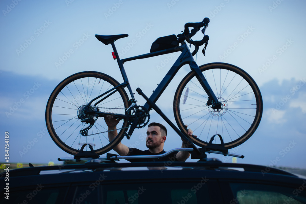 Fototapeta premium Male cyclist loading his bicycle on a rack of his car