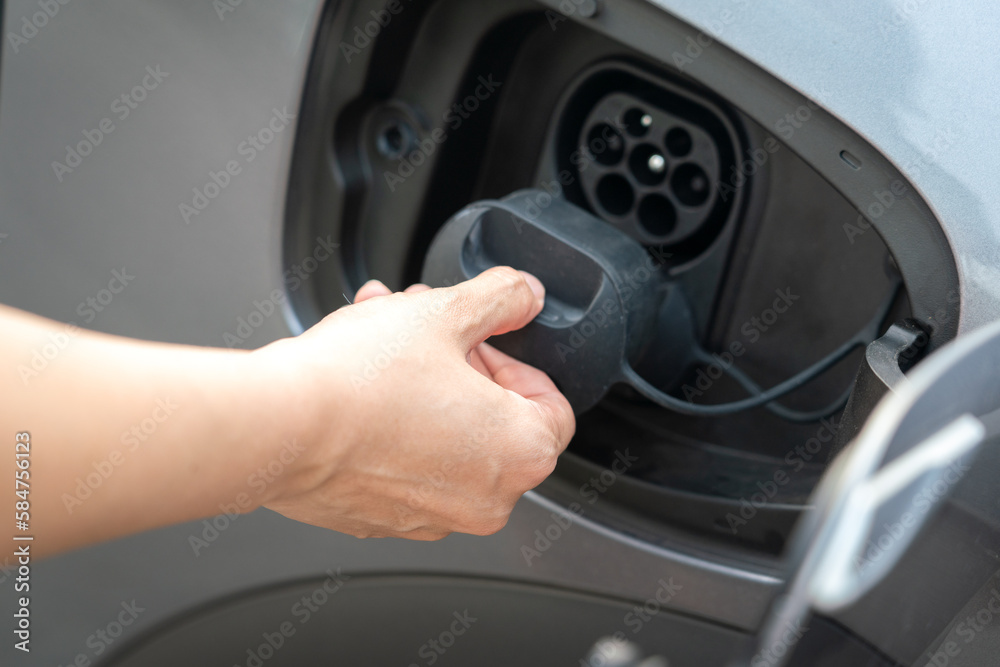 Human hand is opening the CCS DC charging socket's cover of the EV car, transportation action scene. Close-up and selective focus. Human hand is opening the CCS DC charging socket's cover of the EV car, transportation action scene. Close-up and selective focus.