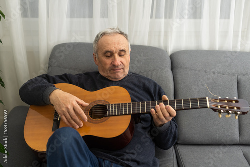 Elderly man playing guitar at home