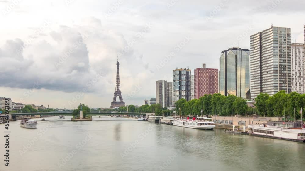 The Eiffel Tower and the Statue of Liberty reflected on water with modern buildings and traffic on road timelapse hyperlapse. View from Mirabeau bridge before sunset. Paris, France The Eiffel Tower and the Statue of Liberty reflected on water with modern buildings and traffic on road timelapse hyperlapse. View from Mirabeau bridge before sunset. Paris, France