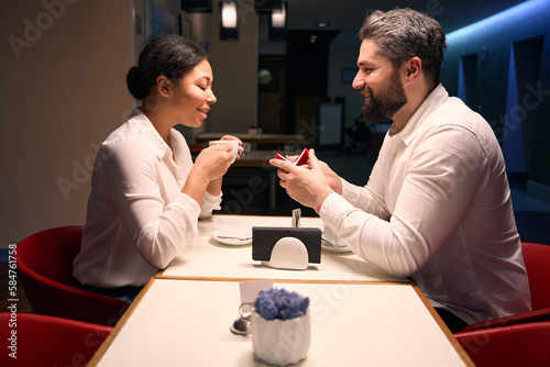 Romantic guy proposing to his beloved woman in coffee shop