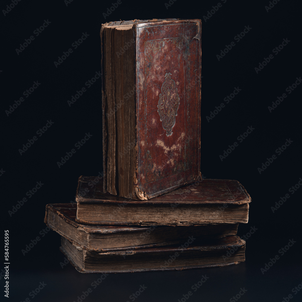 Leather bound book with gold embossing. Torah book standing on stack of old jewish books in the dark. Education and religion concept. Low key. Closeup.
